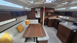Une cuisine compacte avec une table à manger centrale, un petit coin cuisine et un espace salon avec des coussins.