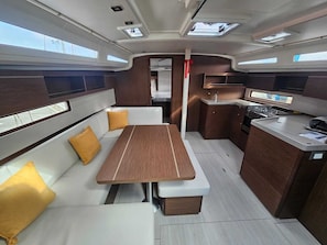 Une cuisine compacte avec une table à manger centrale, un petit coin cuisine et un espace salon avec des coussins.