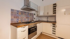 A kitchen with white cabinets, a tiled backsplash, a stove, and a built-in oven. - Casa Gioia by MMega (Florence)