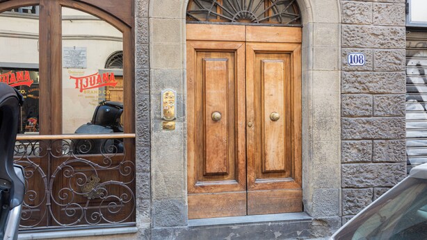 A double wooden door with a metal grill above it, a sign with 'TJUANA' on the left, and a stone wall with a number '108' on the right. - Casa Gioia by MMega (Florence)