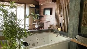 A bathroom with a bathtub, a wooden ceiling, and a stone wall. - DOMAINE COUL'EAU (Eaunes)