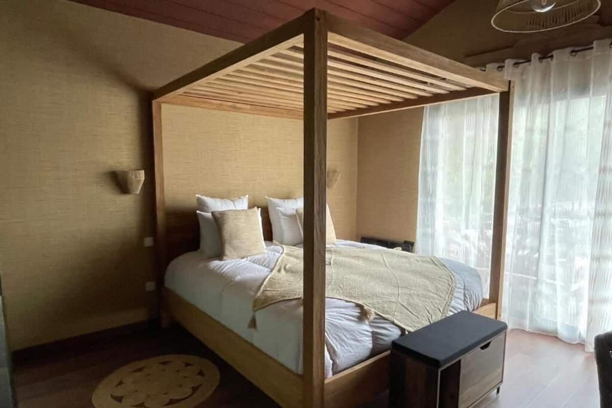 A four-poster bed with a wooden frame, a bedside table, and a round rug on the floor.