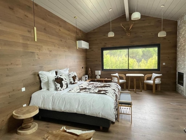 Un intĂ©rieur en bois comprenant un lit, une table, des chaises et une grande fenĂȘtre.
