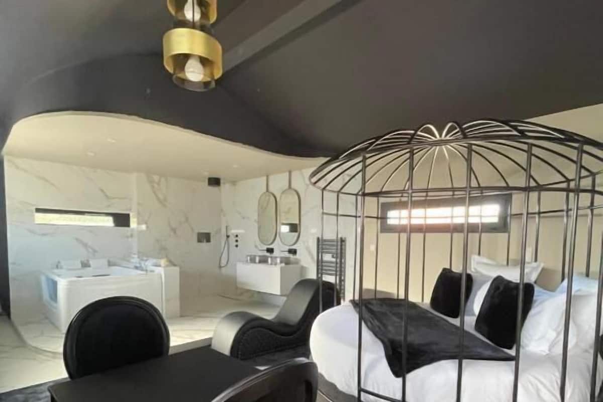 A modern hotel room with a curved bed, a desk, and a chair.