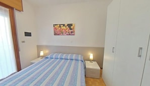 Ein Schlafzimmer mit einem Bett, zwei Nachttischen mit Lampen, einem Kleiderschrank und einem Bild an der Wand.