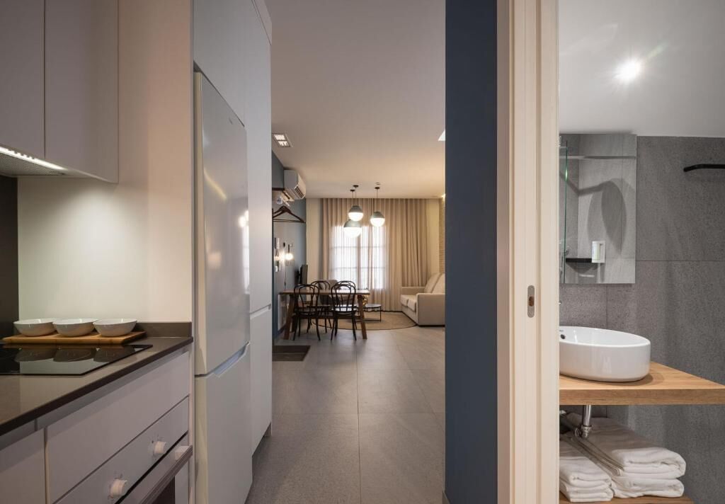 Une cuisine moderne avec un coin repas, un canapé et une salle de bain équipée d’un lavabo et d’un porte-serviettes.