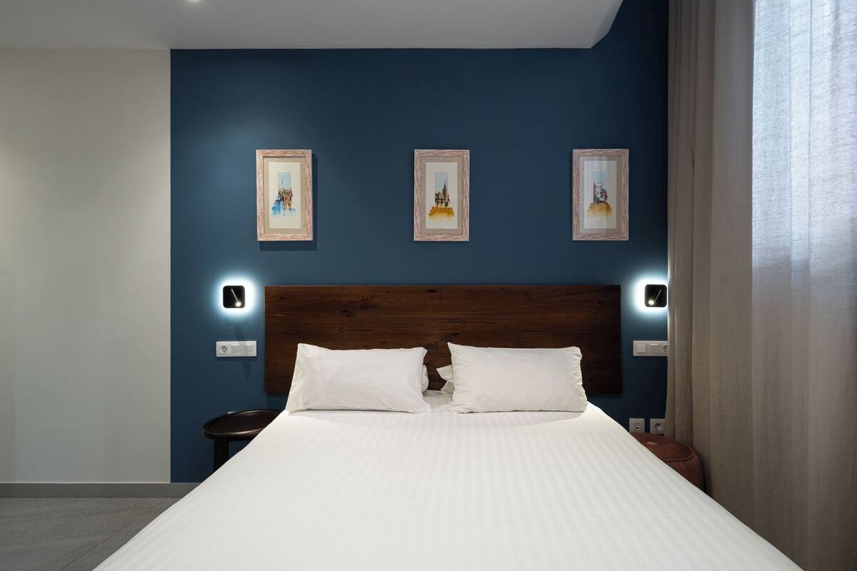 A hotel room with a large bed, a wooden headboard, and three framed pictures on the wall.