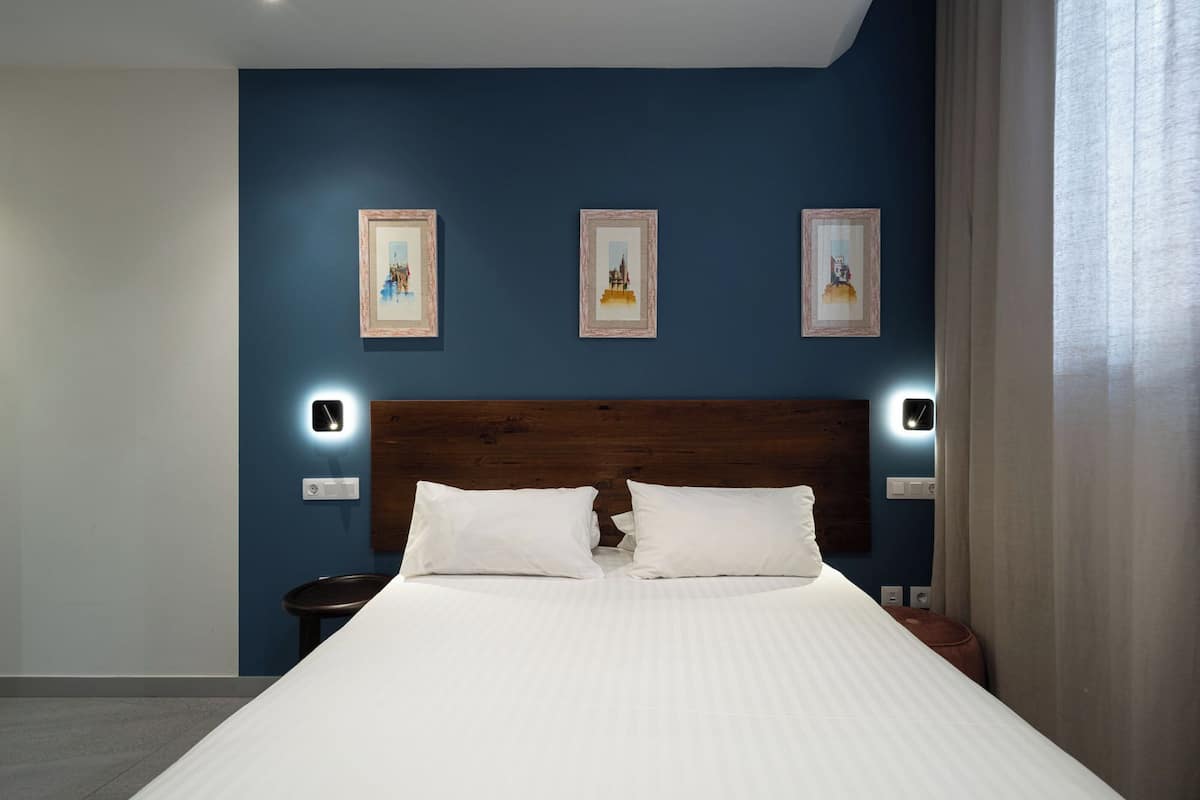 A hotel room with a large bed, a wooden headboard, and three framed pictures on the wall.