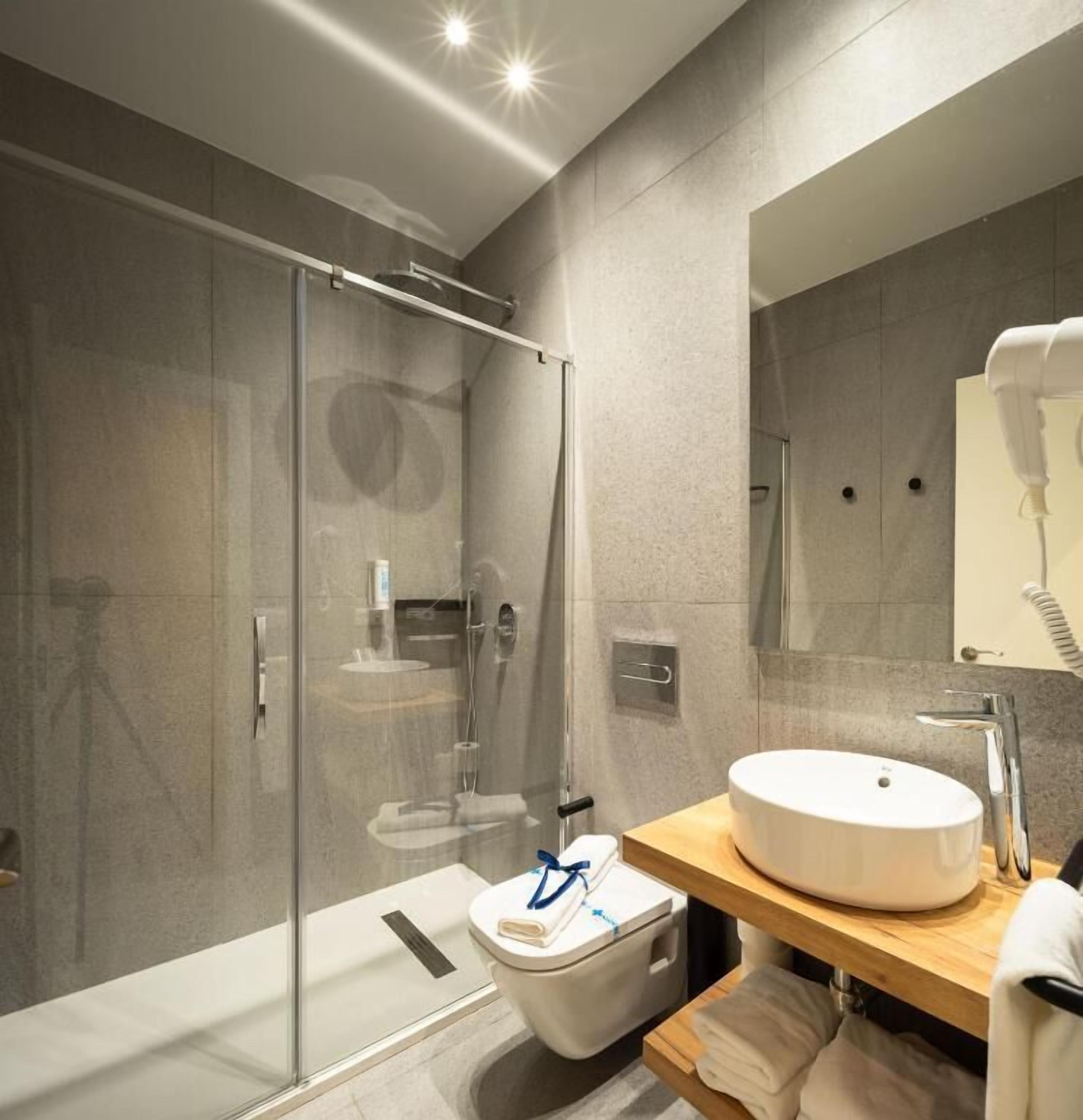 A modern bathroom with a glass-enclosed shower, a white sink, and a mirror above it.