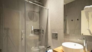 A modern bathroom with a glass-enclosed shower, a white sink, and a mirror above it.