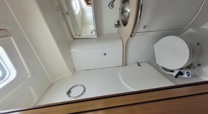 A compact bathroom with a toilet, a sink, and a mirror.