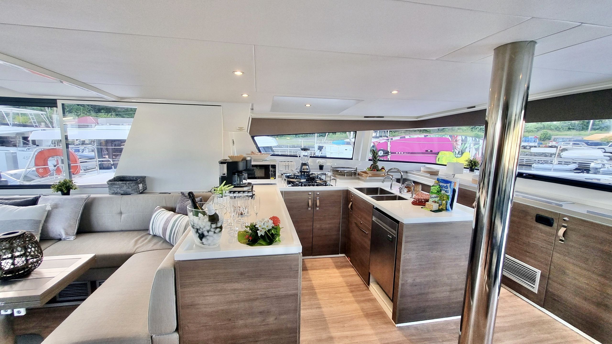 A modern kitchen with a central island, a dining area with a sofa, and a view of the marina.