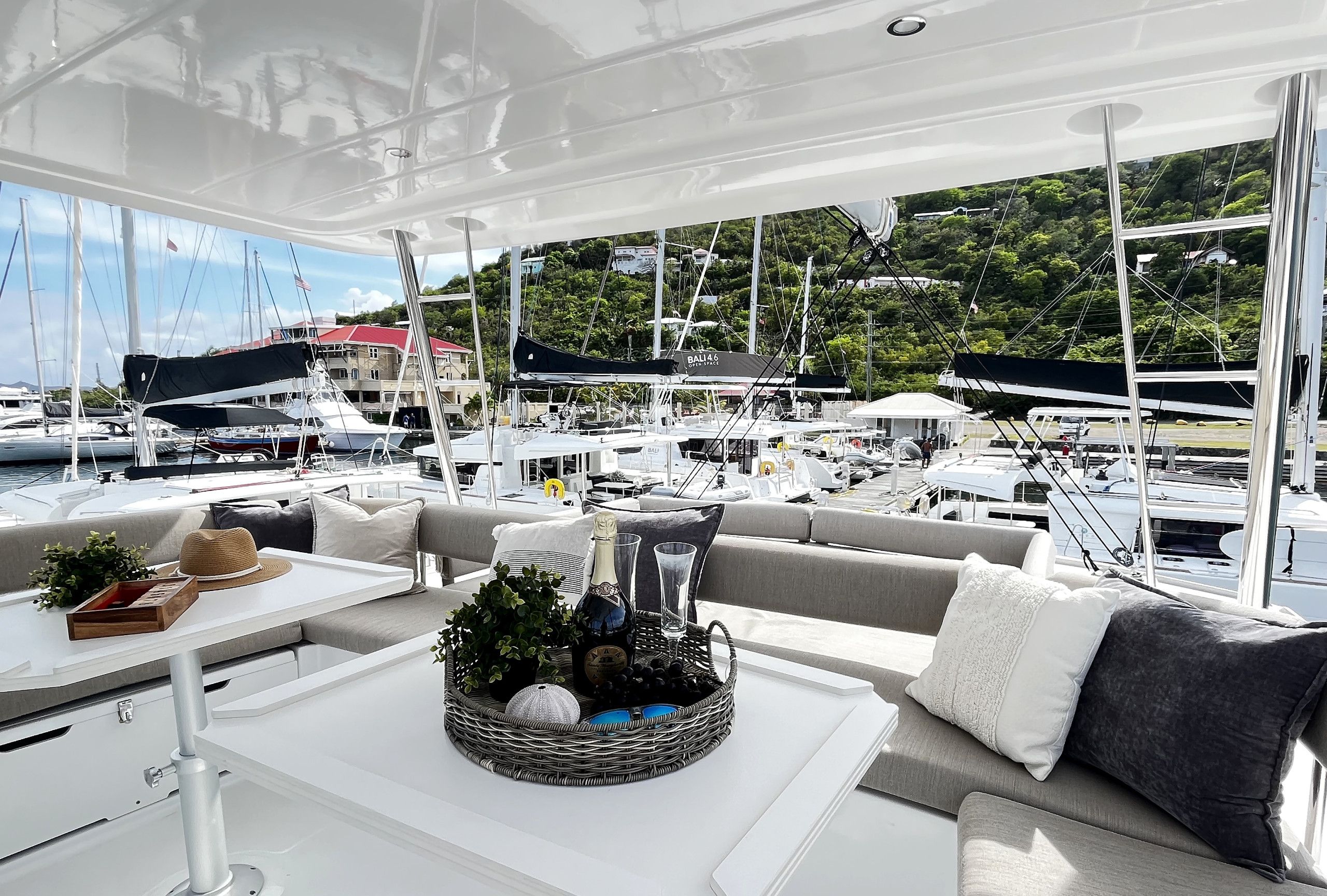 En lyxig inredning i en yacht med en sittgrupp, ett bord med en flaska och glas, och utsikt över andra yachter i en småbåtshamn.