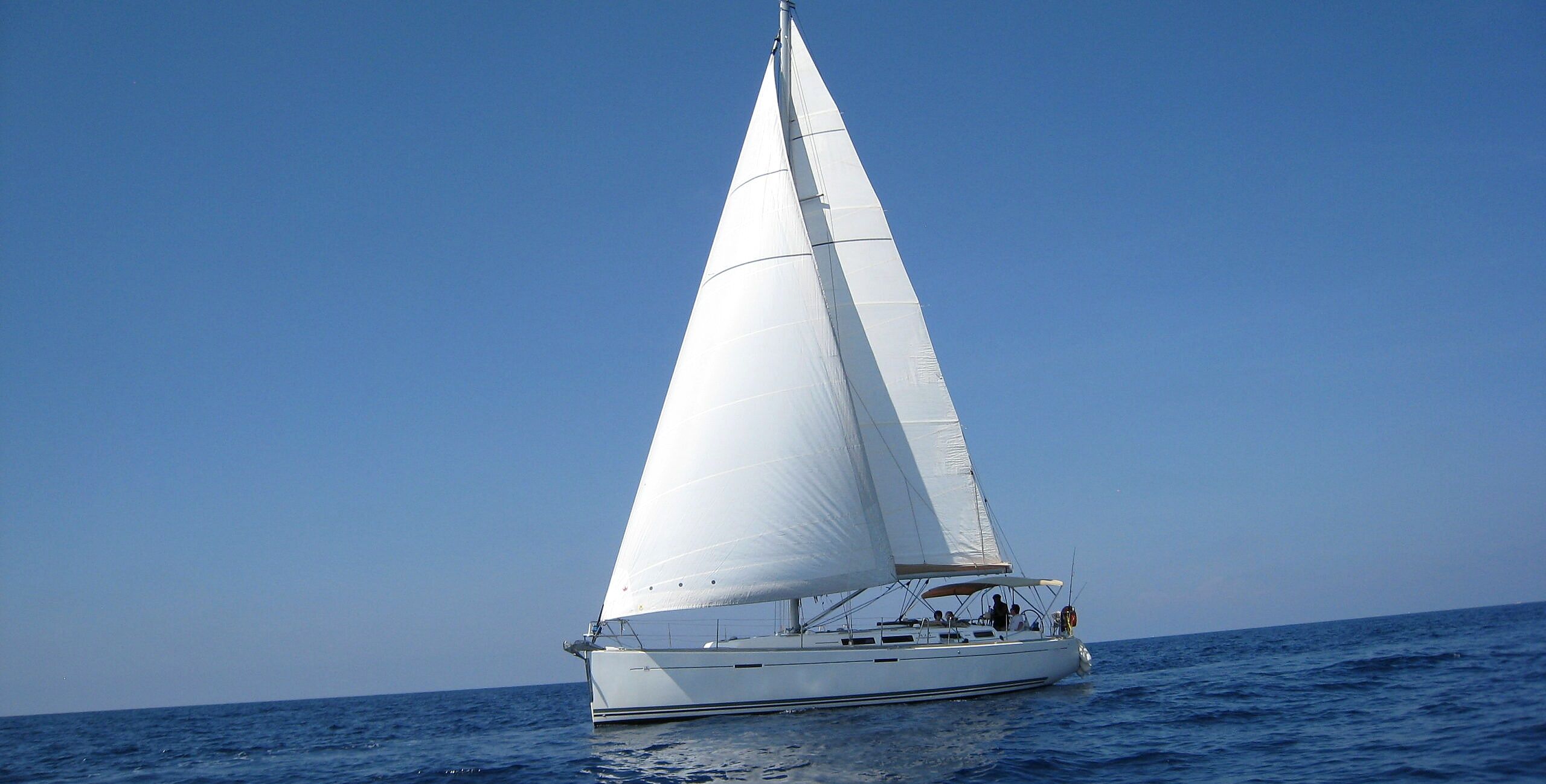 Ein Segelboot mit einer weißen Segel auf dem Wasser.