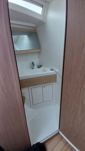 A compact bathroom with a built-in sink, a mirror, and a small storage cabinet.