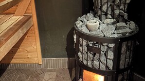 A stone fireplace with a fire, wooden benches, and a dark wall.