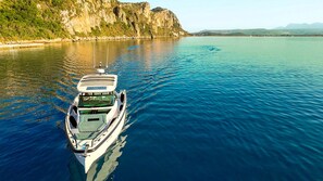 A boat on calm water with a rocky coastline in the background. - Sun-Kissed Sailing Adventure in the Stunning Islas Cícladas (Paros)