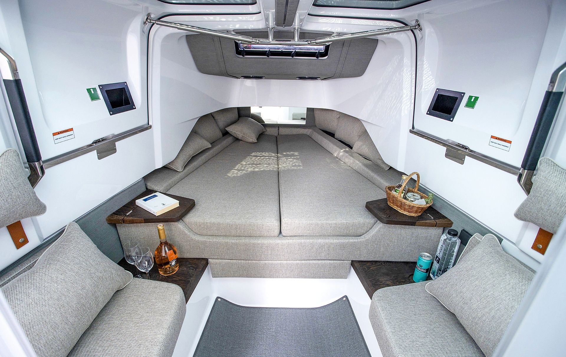 A compact living space with a sofa set, a small table with a bottle and glasses, and a wall-mounted control panel.