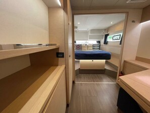 Ein kompakter, gut beleuchteter Innenraum mit einem Bett, Ablagefächern und einem Fernseher.