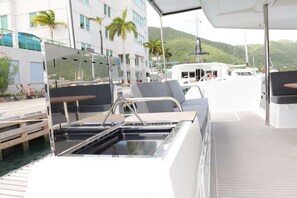 A boat deck with seating, a water feature, and a view of buildings and hills. - Caribbean Dream: Sun-soaked Sailing Adventure from Tortola, Islas Vírgenes Británicas (Road Town)