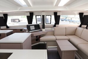 A modern interior with a sofa, a small table, a TV, and windows. - Caribbean Dream: Sun-soaked Sailing Adventure from Tortola, Islas Vírgenes Británicas (Road Town)
