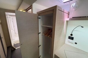 A room with a wooden wardrobe, a mirror, and a wall-mounted light fixture. - Caribbean Dream: Sun-soaked Sailing Adventure from Tortola, Islas Vírgenes Británicas (Road Town)