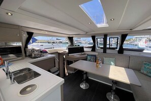 A yacht interior with a kitchen, dining area, and seating. - Caribbean Dream: Sun-soaked Sailing Adventure from Tortola, Islas Vírgenes Británicas (Road Town)