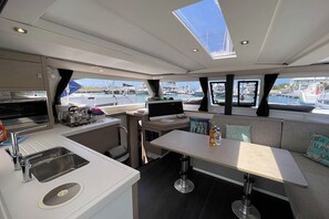 A yacht interior with a kitchen, dining area, and seating. - Caribbean Dream: Sun-soaked Sailing Adventure from Tortola, Islas Vírgenes Británicas (Road Town)