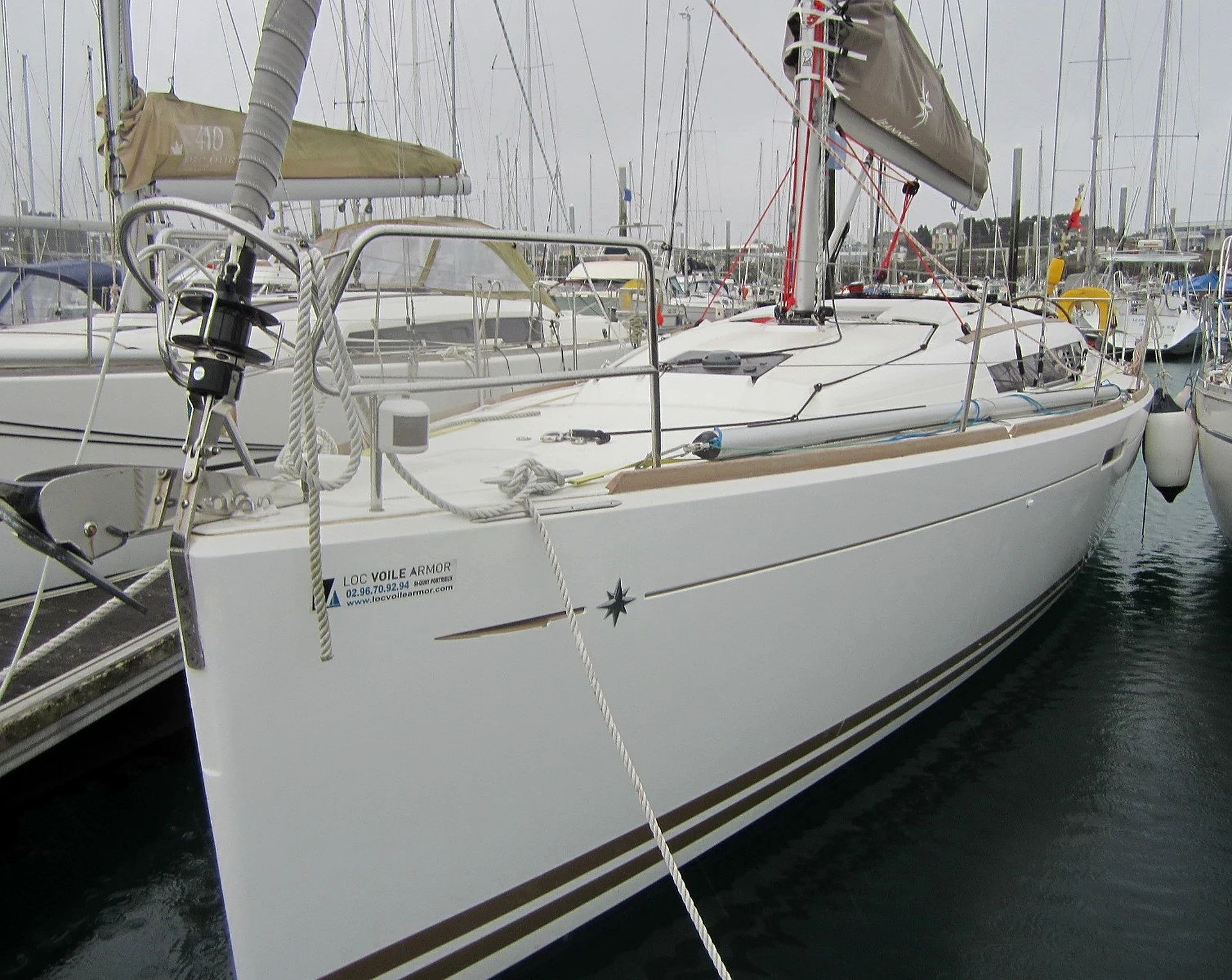 A sailboat docked at a marina with multiple masts and rigging.