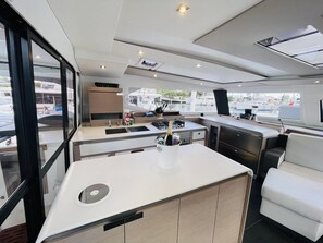 A modern kitchen with a central island, a built-in sink, and a window overlooking a marina. - Caribbean Dream: Sun-soaked Sailing Adventure from Tortola, Islas Vírgenes Británicas (Road Town)