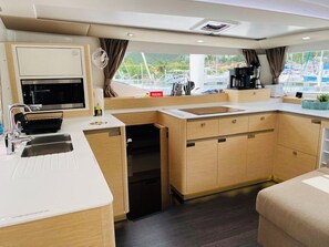 A compact kitchen with a microwave, sink, and coffee maker, featuring a view of a marina. - Caribbean Dream: Sun-soaked Sailing Adventure from Tortola, Islas Vírgenes Británicas (Road Town)