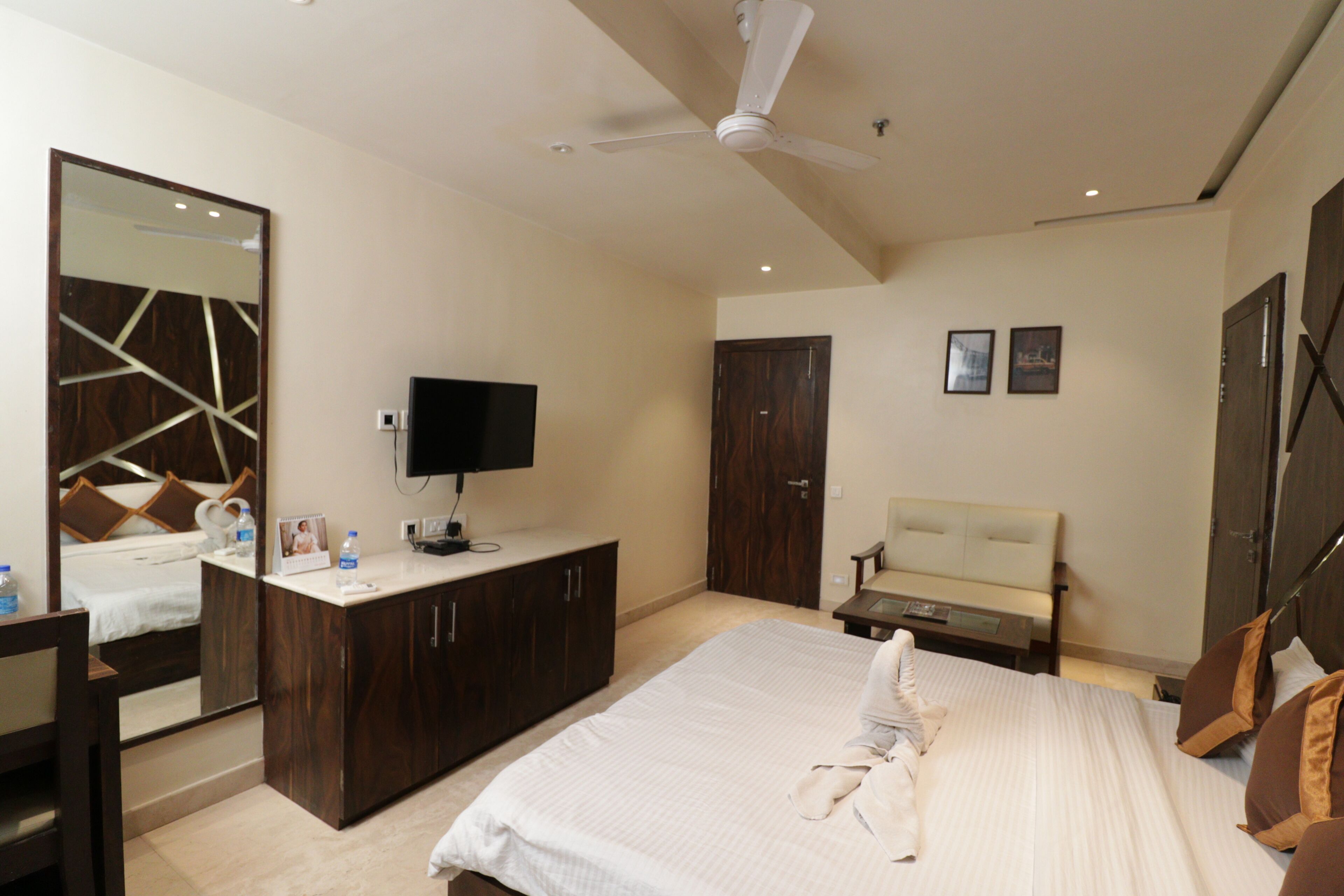 Una habitación de hotel con cama, televisor, escritorio, espejo y armario.