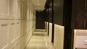 A corridor with a polished floor, white paneling on one side, and dark wooden doors on the other. - EENNRA GUEST HOUSE, Malda (Malda)