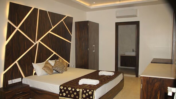 A bedroom with a large bed, a wardrobe, a mirror, and a nightstand. - EENNRA GUEST HOUSE, Malda (Malda)