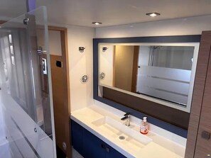 A bathroom with a large mirror, a sink, and a shower door.