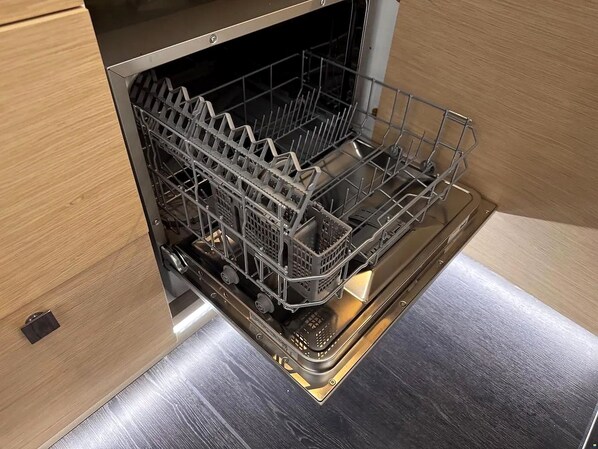 A dishwasher with a stainless steel finish, located in a kitchen with wooden cabinetry.