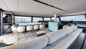 Interni moderni di uno yacht con zona pranzo, posti a sedere e postazione di comando.