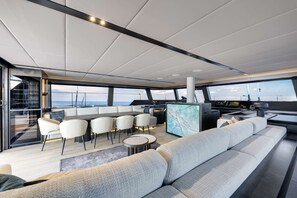 A modern yacht interior with a dining area, seating, and a control station. - Sun-Kissed Sailing Adventure in Islas Sarónicas (Alimos)