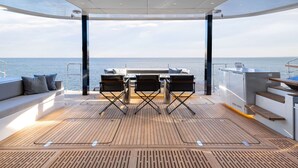 Un terrazzo con tavolo e sedie, un divano con cuscini e vista sul mare.