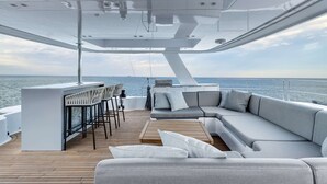Interni moderni di uno yacht con zona bar, posti a sedere e vista sul mare.