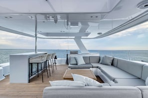 Un intérieur de yacht moderne comprenant un bar, des sièges et une vue sur la mer.