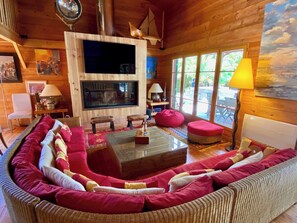 A cozy living room with a curved sofa, a fireplace, and a large window. - Charming villa with pool & idyllic terrace A3691 (Lège-Cap-Ferret)