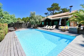A swimming pool with lounge chairs and a wooden deck. - Charming villa with pool & idyllic terrace A3691 (Lège-Cap-Ferret)