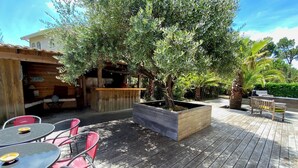 Eine Terrasse im Freien mit Holzmöbeln, einem integrierten Blumenkasten und einer rustikalen Holzkonstruktion.