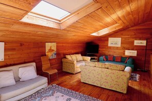 A cozy cabin interior with a wooden ceiling, a sofa, a chair, and a television. - Charming villa with pool & idyllic terrace A3691 (Lège-Cap-Ferret)