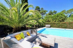 A swimming pool with a wooden deck and seating area. - Charming villa with pool & idyllic terrace A3691 (Lège-Cap-Ferret)