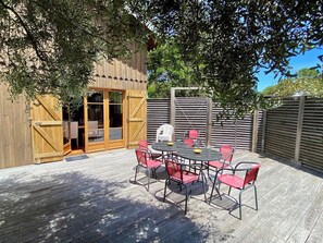An outdoor patio with a round table and chairs, a wooden door, and a fence. - Charming villa with pool & idyllic terrace A3691 (Lège-Cap-Ferret)