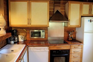 A compact kitchen with wooden cabinets, a microwave, a stove, and a dishwasher. - Charming villa with pool & idyllic terrace A3691 (Lège-Cap-Ferret)