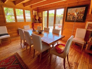 A wooden interior with a dining table surrounded by chairs, a red cushion, and a painting on the wall. - Charming villa with pool & idyllic terrace A3691 (Lège-Cap-Ferret)