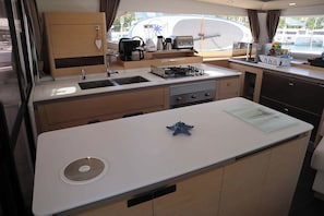 A compact kitchen with a sink, stove, and various appliances. - Sun-Kissed Sailing Adventure in Isla de Mahe, Seychelles (Victoria)